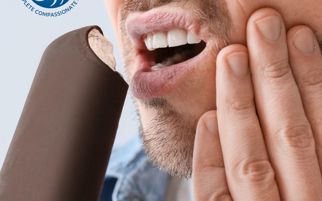 Man touching his face with tooth pain while eating a popsicle